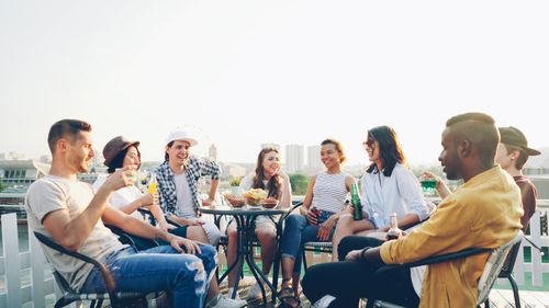 Free A diverse group of friends enjoying a rooftop gathering with drinks and snacks. Stock Photo