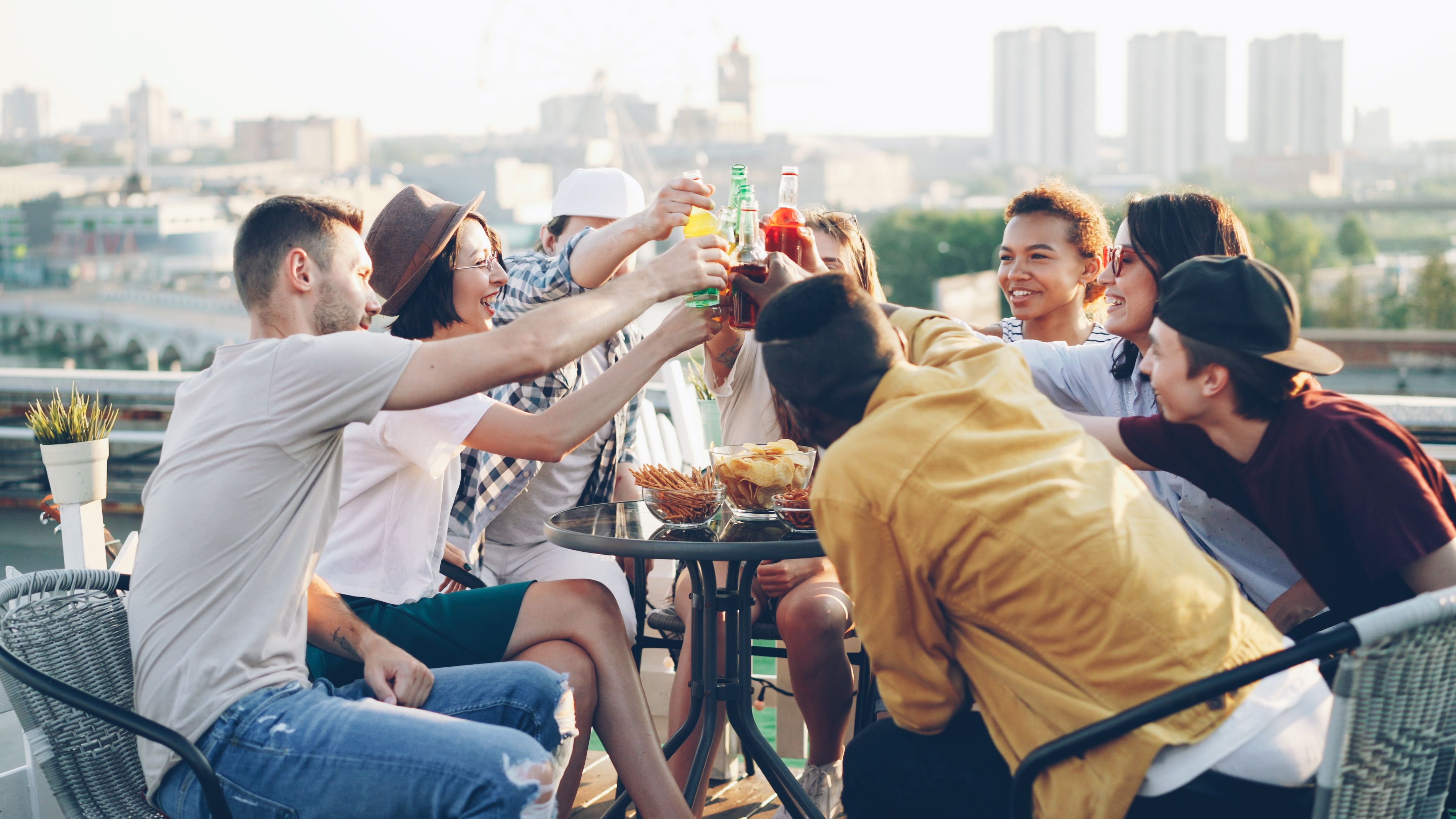 Gratuit Un groupe d'amis de tous horizons trinque avec des boissons lors d'une réception ensoleillée sur un toit-terrasse. Photos