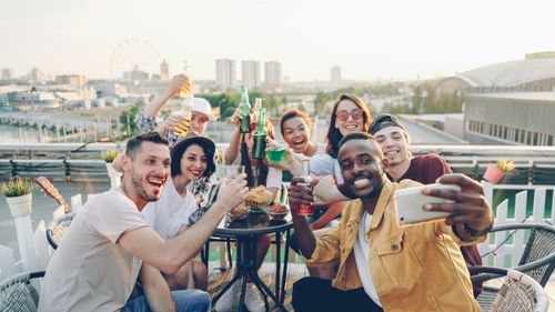 Free Group of friends enjoying a lively rooftop party with drinks and laughter. Stock Photo