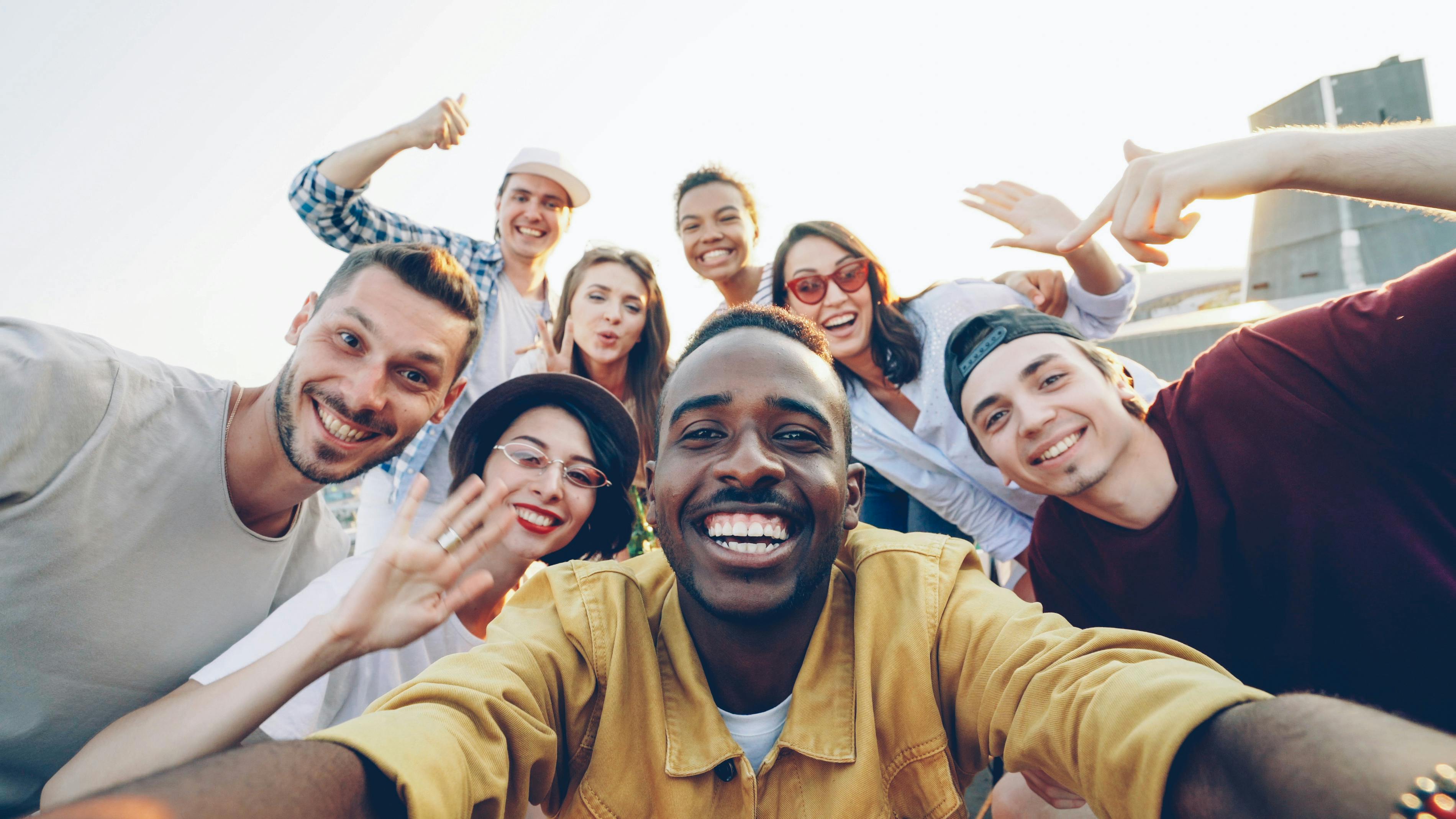 Diverse group of friends smiling and enjoying an outdoor gathering, capturing a joyful moment.