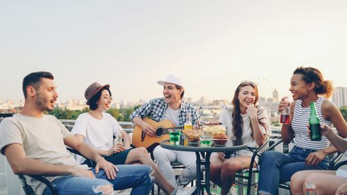 Free Group of friends having fun at a rooftop gathering with music and drinks. Stock Photo