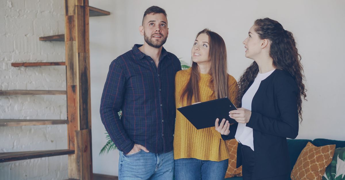 Young couple exploring a new home with their real estate agent, discussing options and features.