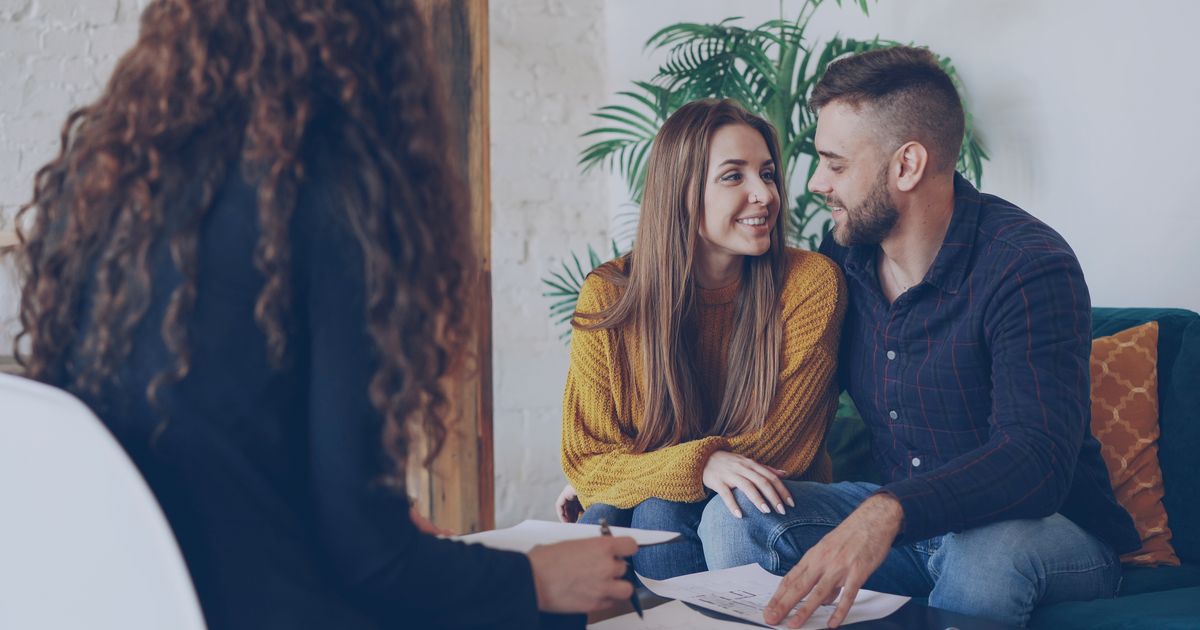 A young couple discussing plans with an advisor in a modern office setting.