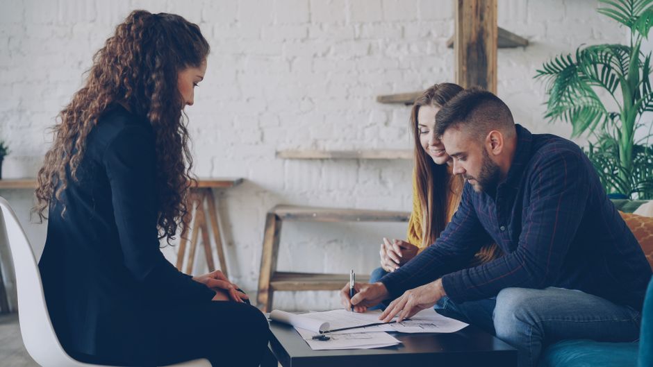 Dos mujeres y un hombre involucrados en una reunión colaborativa en un espacio de oficina moderna.