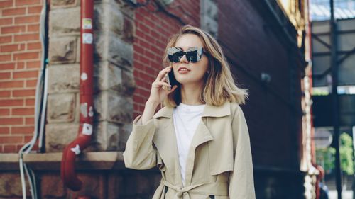 Free Fashionable woman in sunglasses using smartphone outdoors. Stock Photo