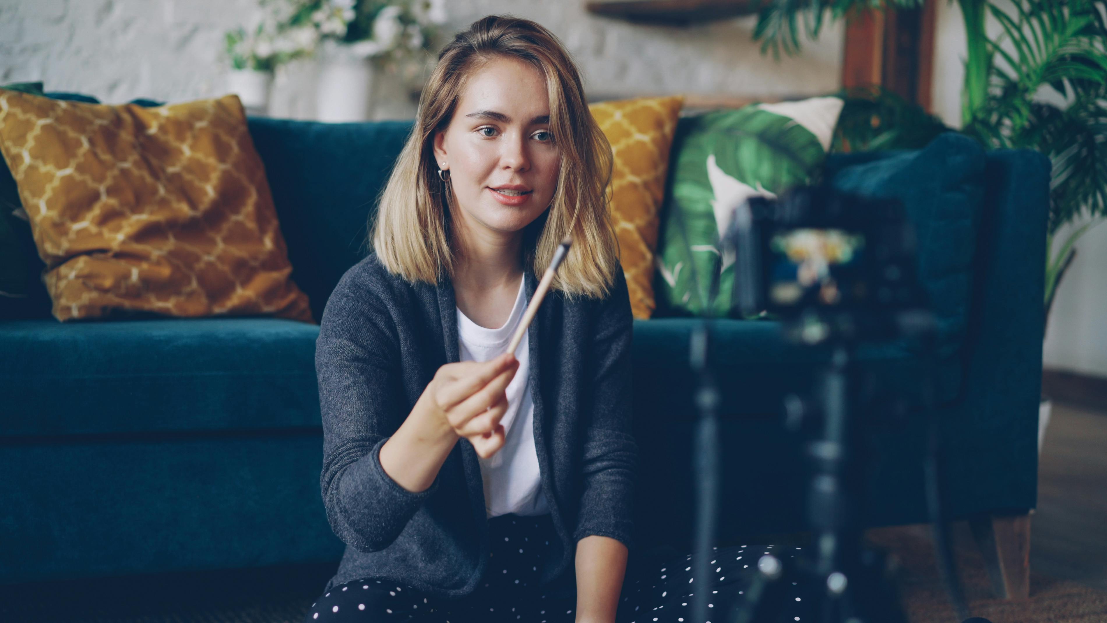 Woman filming video content in a cozy living room setting.