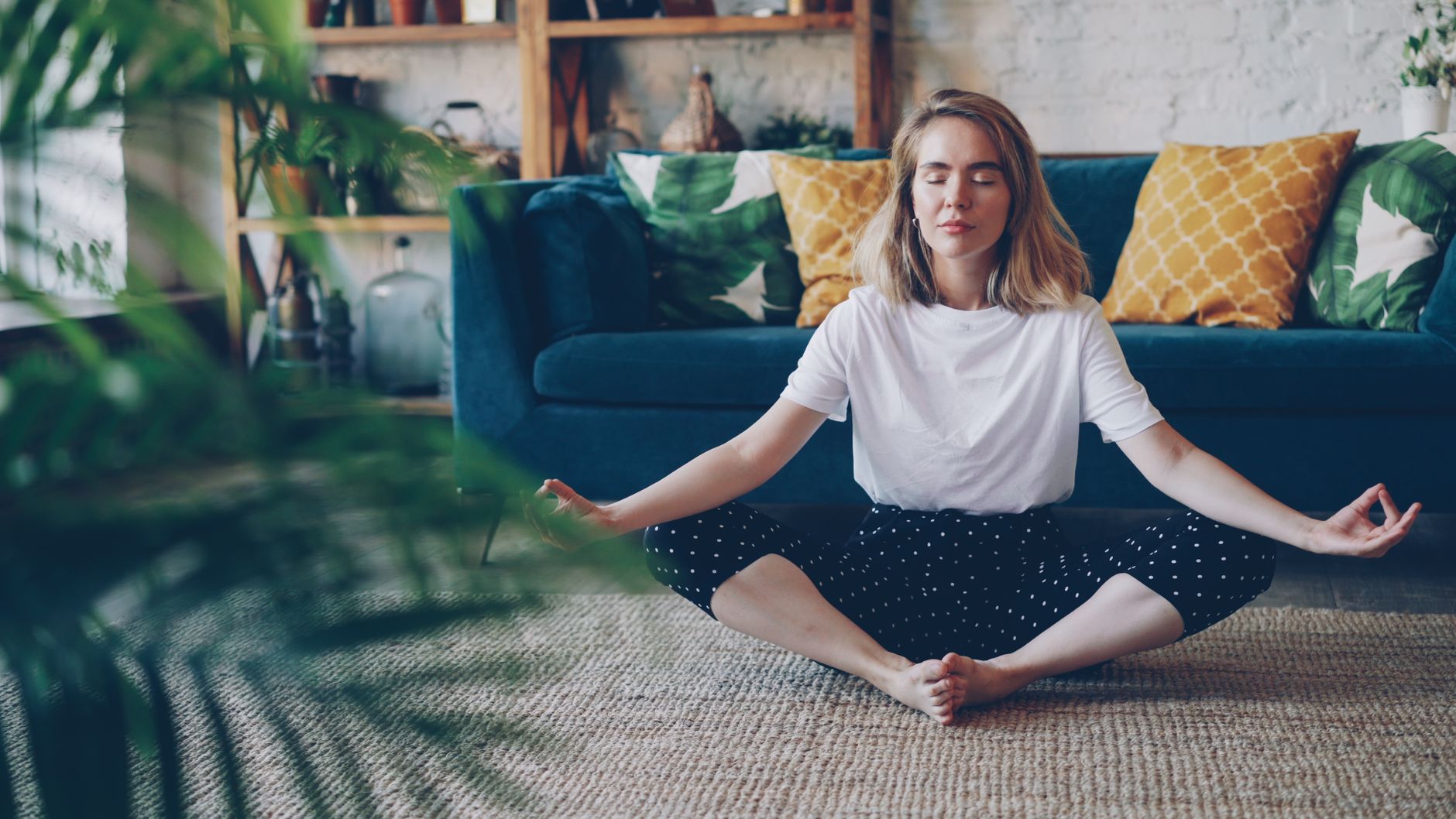 Woman meditating in a cozy living room setting, emphasizing relaxation and mindfulness.