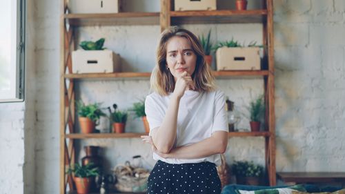 Free Woman standing thoughtfully in cozy room with plants. Stock Photo