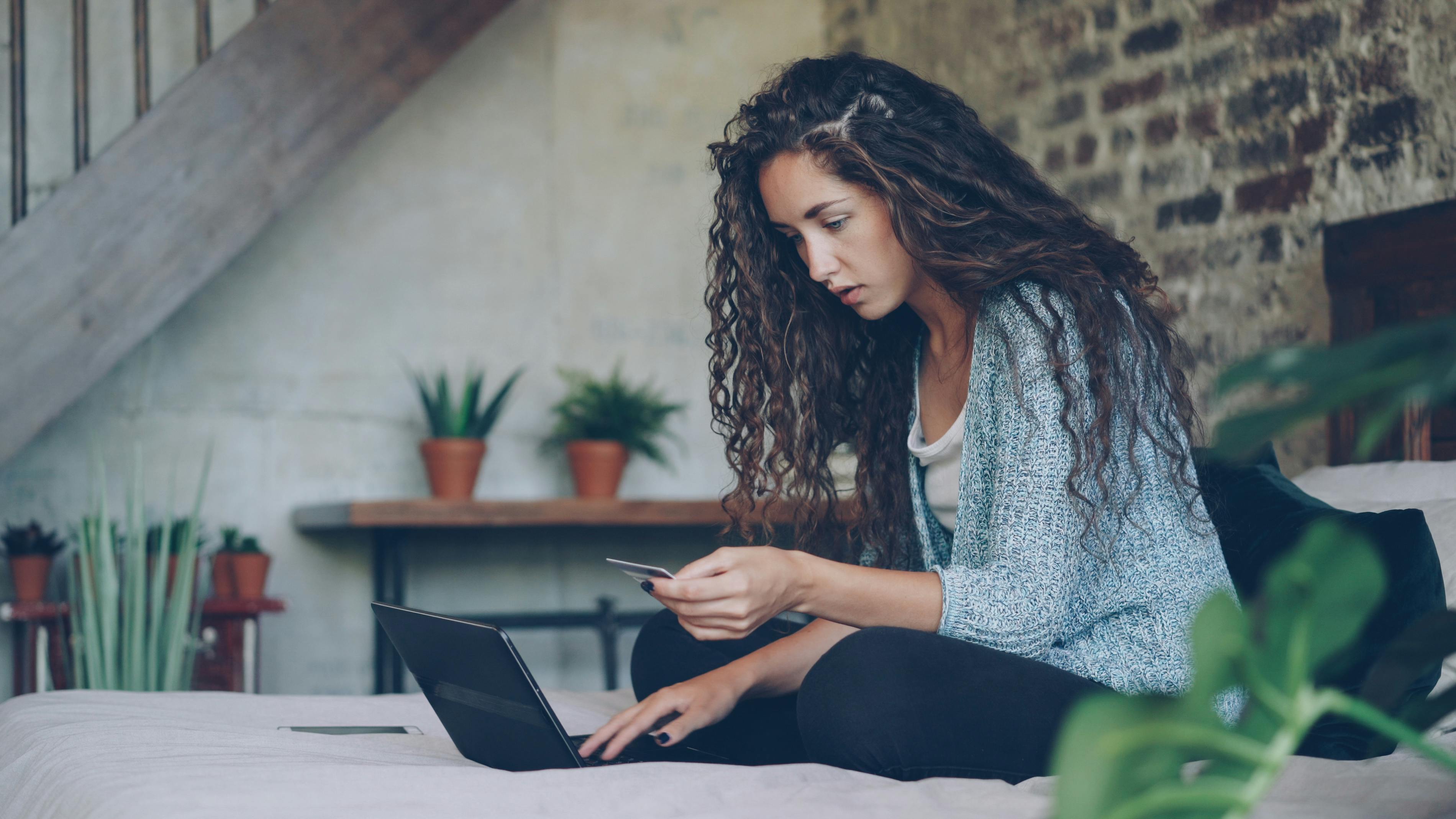 Young woman using laptop and credit card for online shopping at home.