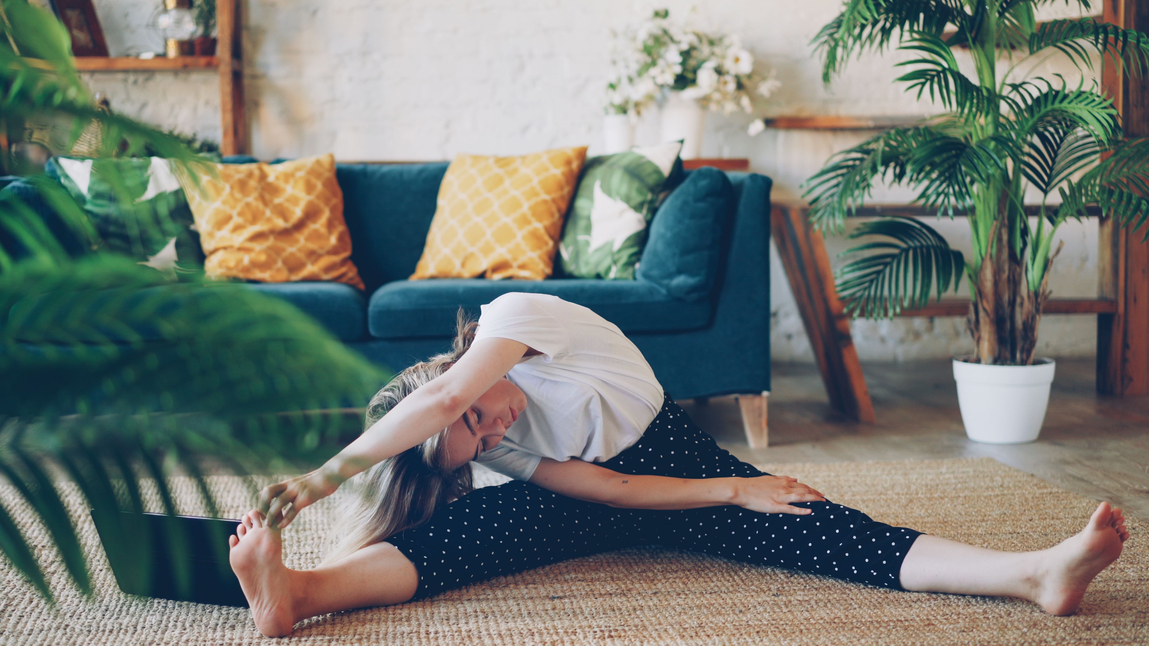 Young woman practicing yoga and stretching indoors in a cozy living room.