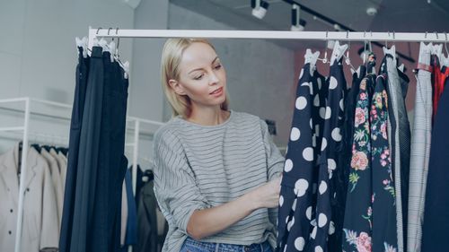 Free A woman browses through fashionable dresses on a rack in a clothing store. Stock Photo