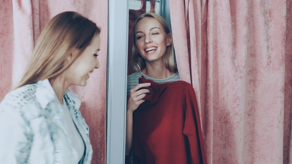 Como a Despersonalização Pode Impactar sua Autoestima 2 Two women enjoying a shopping experience, smiling in a changing room.