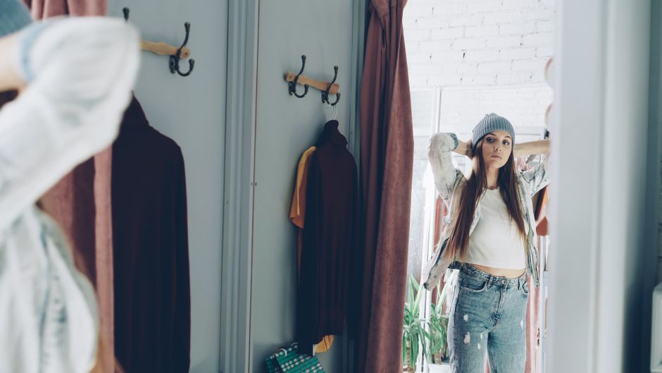 Fashionable woman in a dressing room checking her fit in the mirror.
