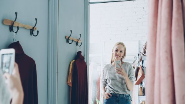Woman taking a mirror selfie in a cozy room with stylish decor and relaxed ambiance.