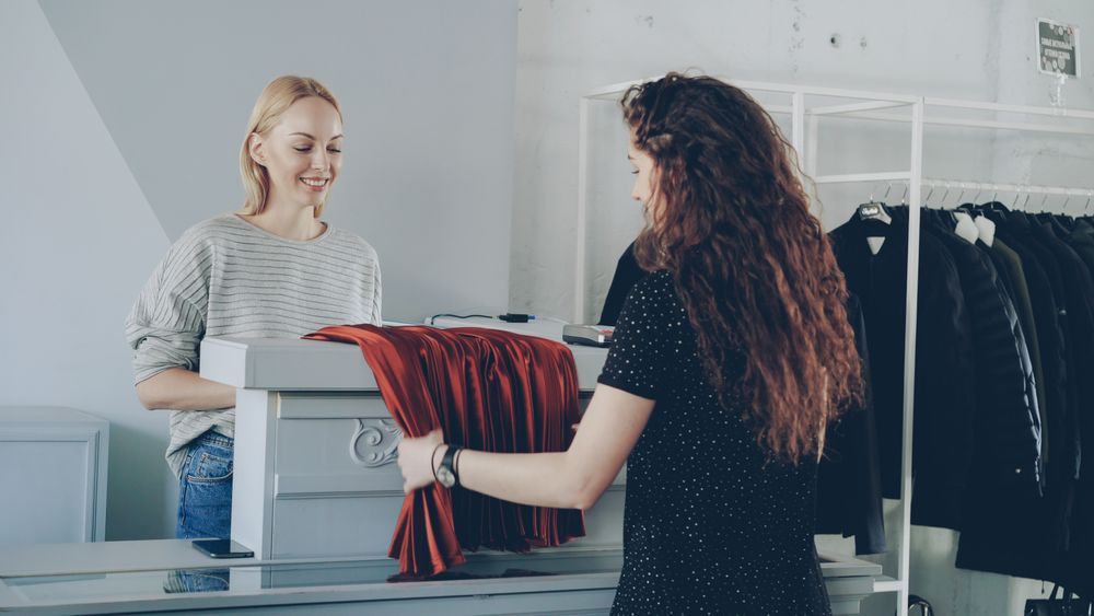 Shop assistant folding a garment for a customer at the counter — photo by Vitaly Gariev on Pexels