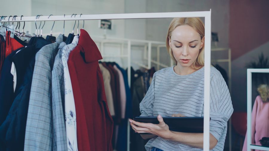 Salesperson using a tablet to manage product information in a clothing store