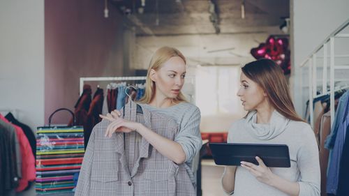Free Two women in trendy boutique discussing clothing and style options, holding a plaid jacket. Stock Photo