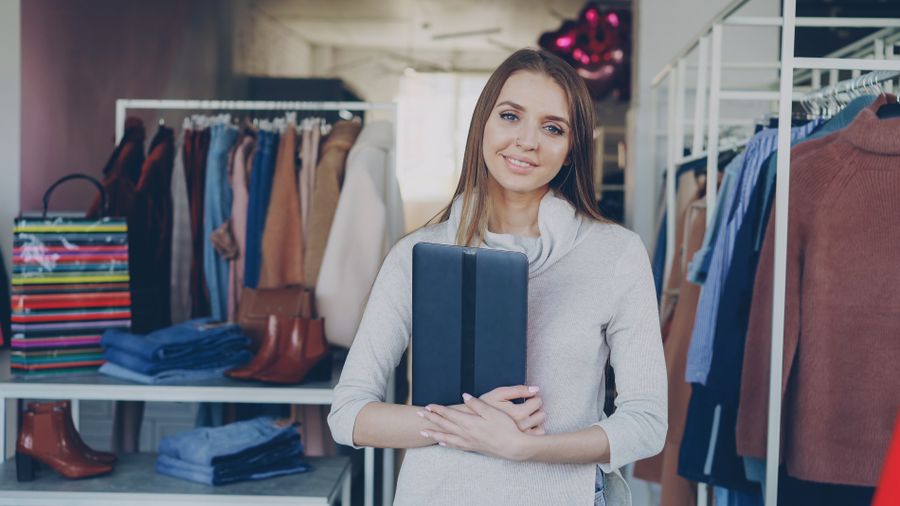Shopkeeper standing among the rails of her clothing store — Vitaly Gariev on Pexels