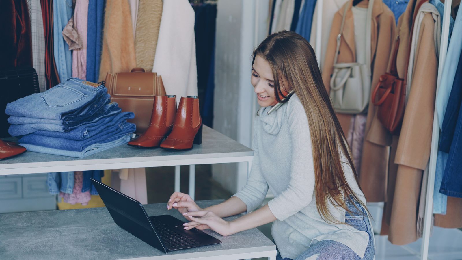 Gestora de loja utilizando telefone e notebook em ambiente de varejo