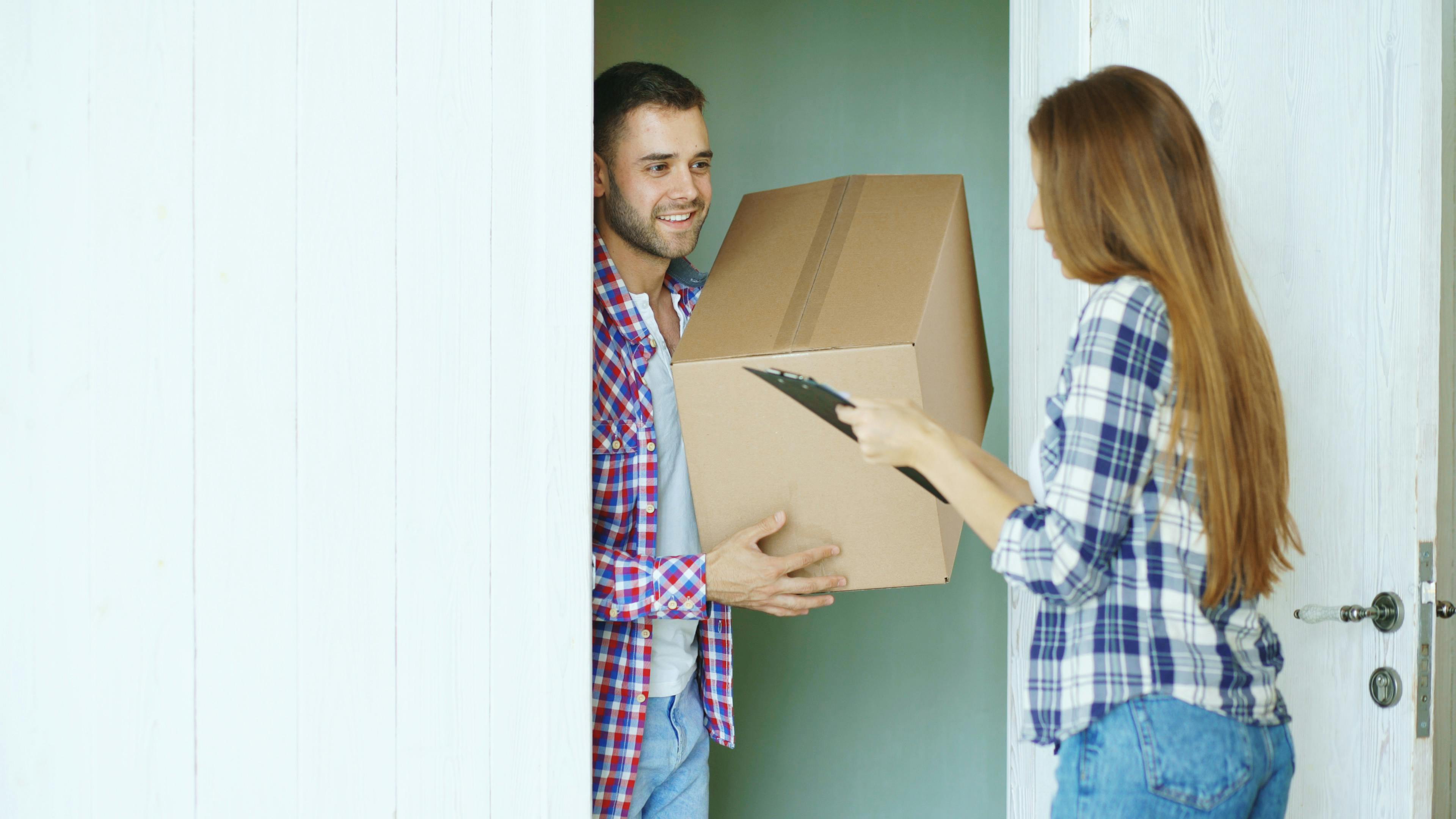 Two people exchanging a cardboard box at the door, representing delivery service.