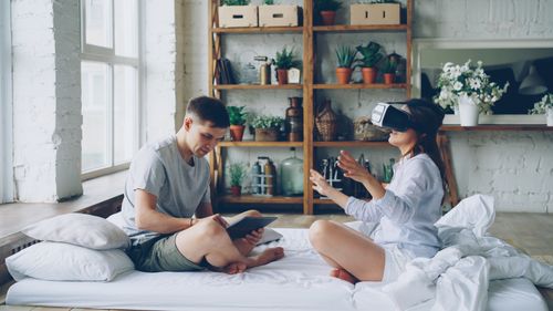 Free Couple enjoying virtual reality and reading in modern cozy home interior. Stock Photo