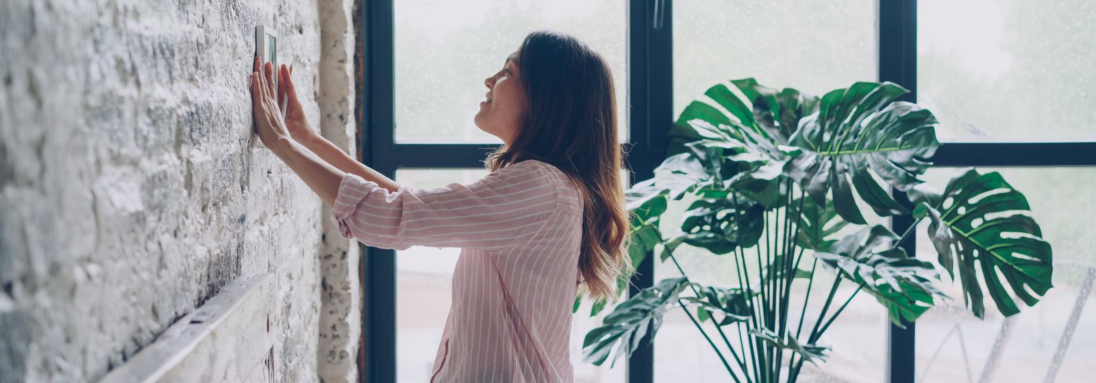 Woman adjusting the thermostat at home