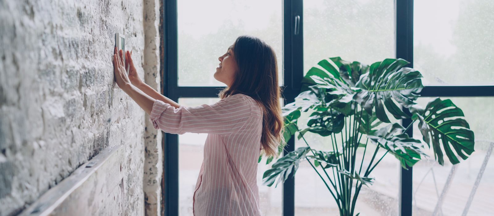 Woman adjusting the thermostat at home