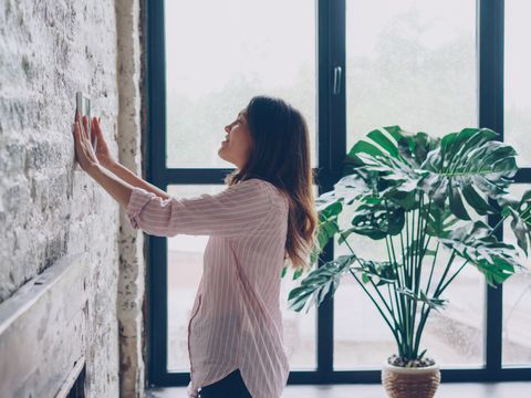 Woman adjusting the thermostat at home