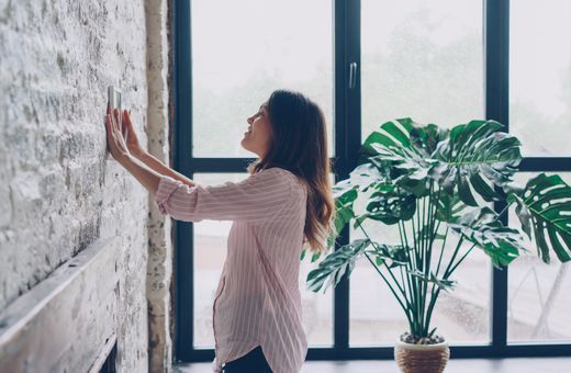 Woman adjusting the thermostat at home