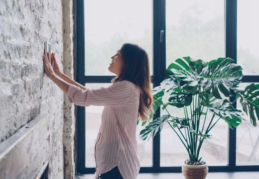 Woman adjusting the thermostat at home