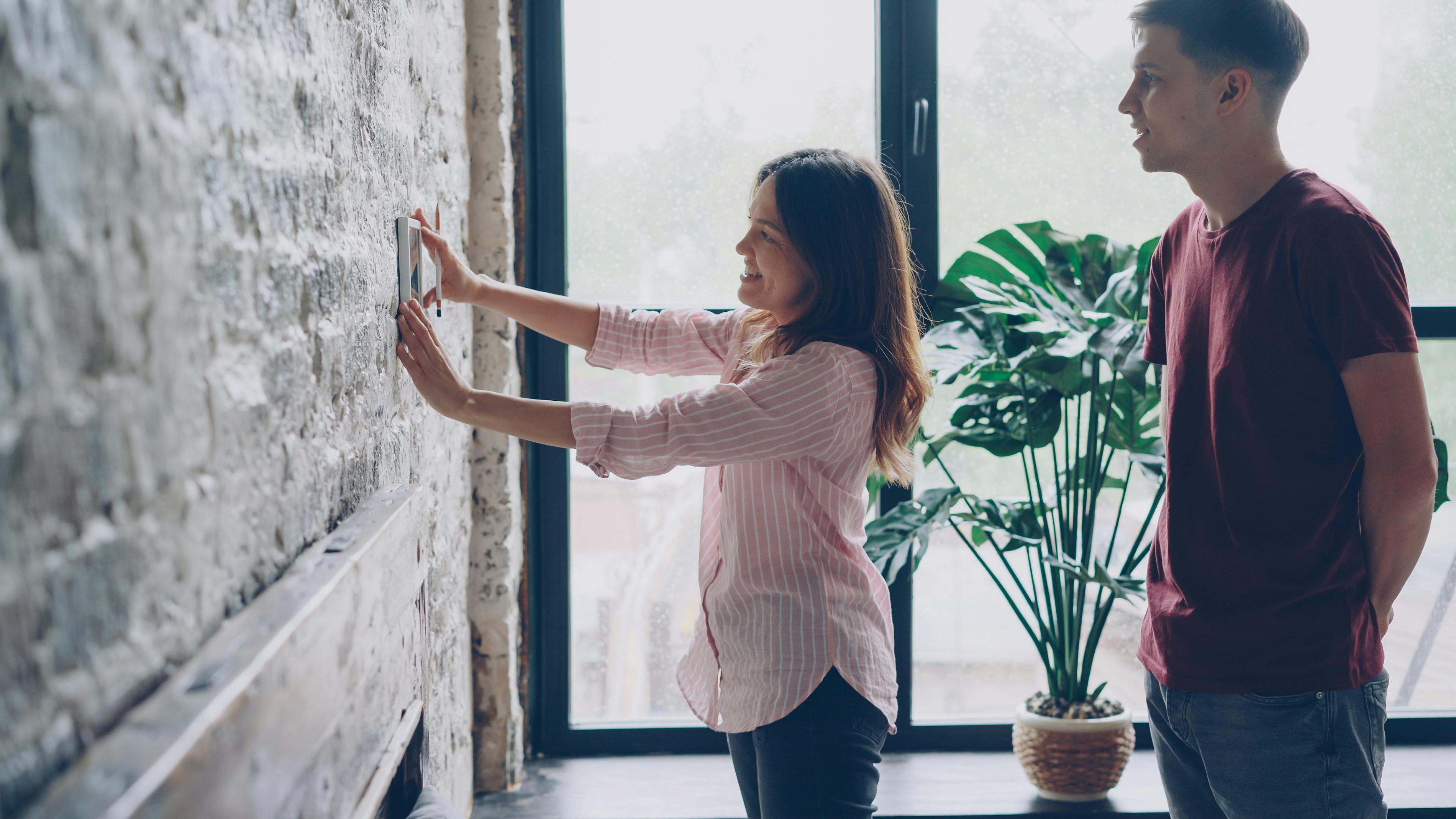 a homeowner in a bright living room using a smartphone app to adjust their home temperature - best thermostat strategies for