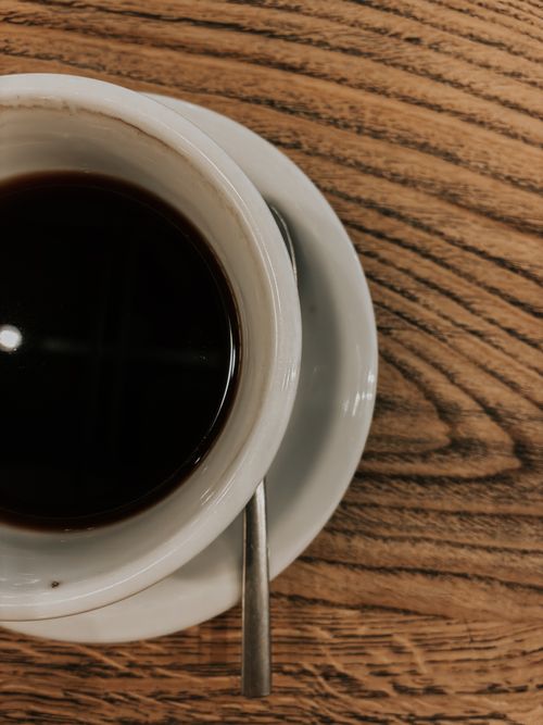 Free Minimalist photo of black coffee in a white cup on a wooden table, offering warmth. Stock Photo