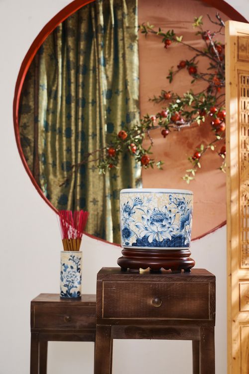 Free Elegant display of traditional Asian vases on wooden tables with a circular backdrop and floral decorations. Stock Photo