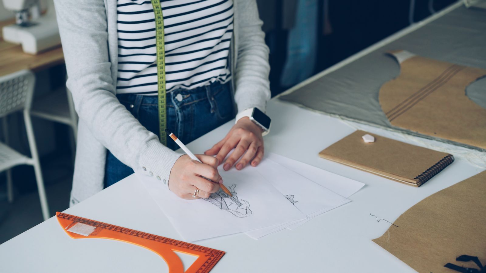 Designer sketching a garment at a pattern table