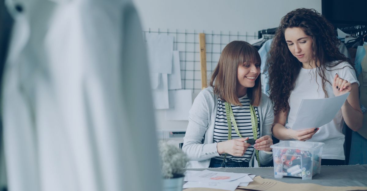 Two women discussing designs in a fashion studio, collaborating over sewing patterns.