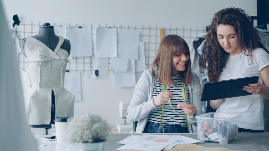 Two fashion designers working together in a studio, designing a new dress.