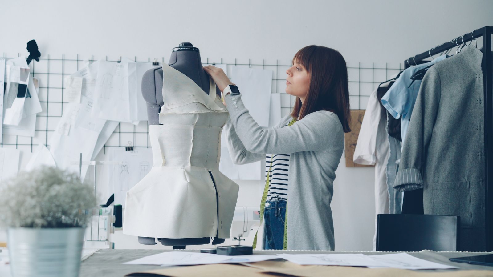 Fashion designer adjusting dress on mannequin in studio