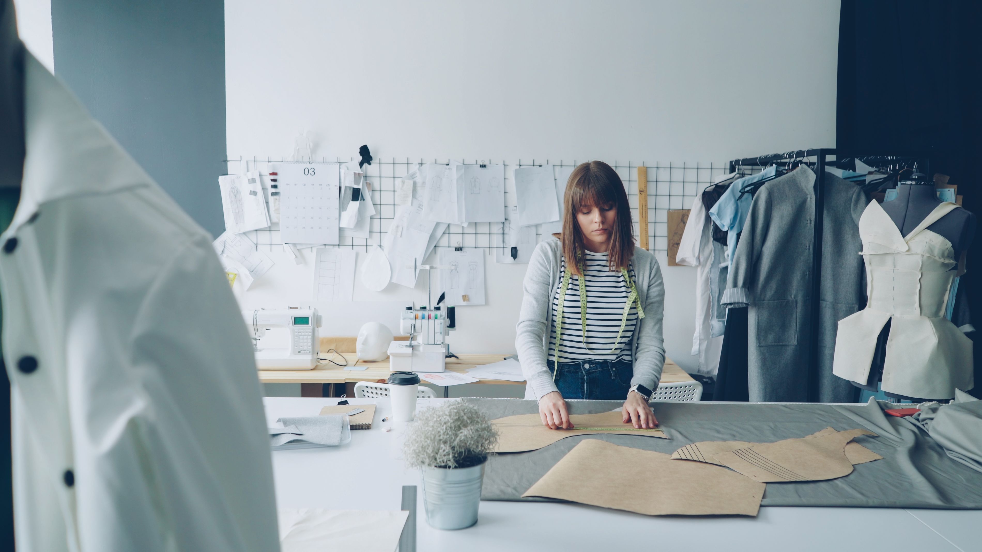 A fashion designer works on patterns in a creative studio environment.