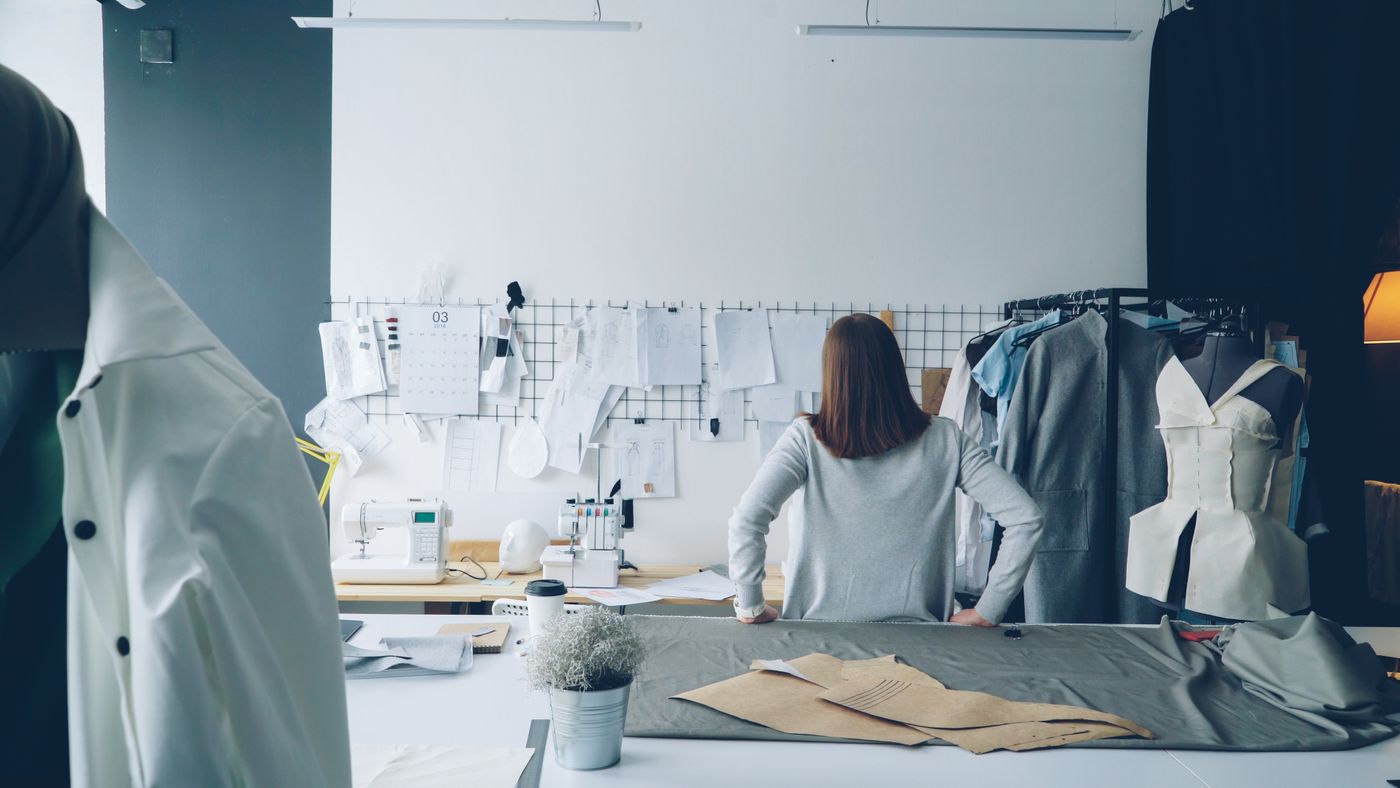 A designer at work in a studio, patterns and part-made garments around them