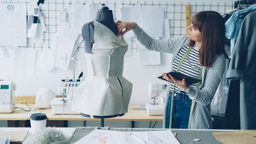 Free Female designer working on dress in studio with mannequin and patterns, fashion craft. Stock Photo