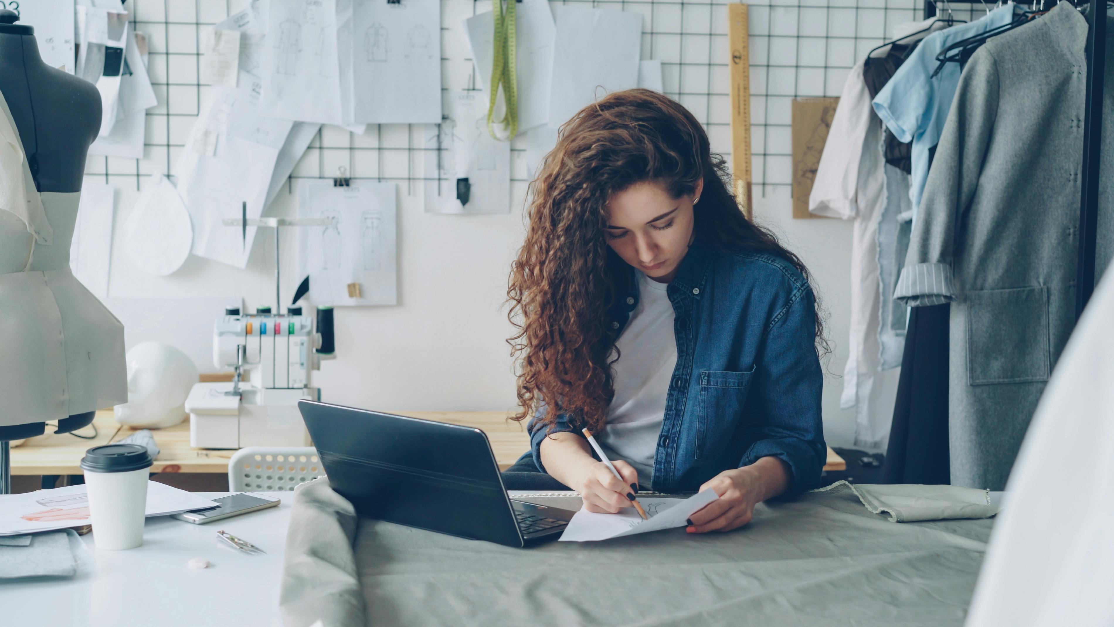 Female designer sketching fashion ideas in a creative workspace.