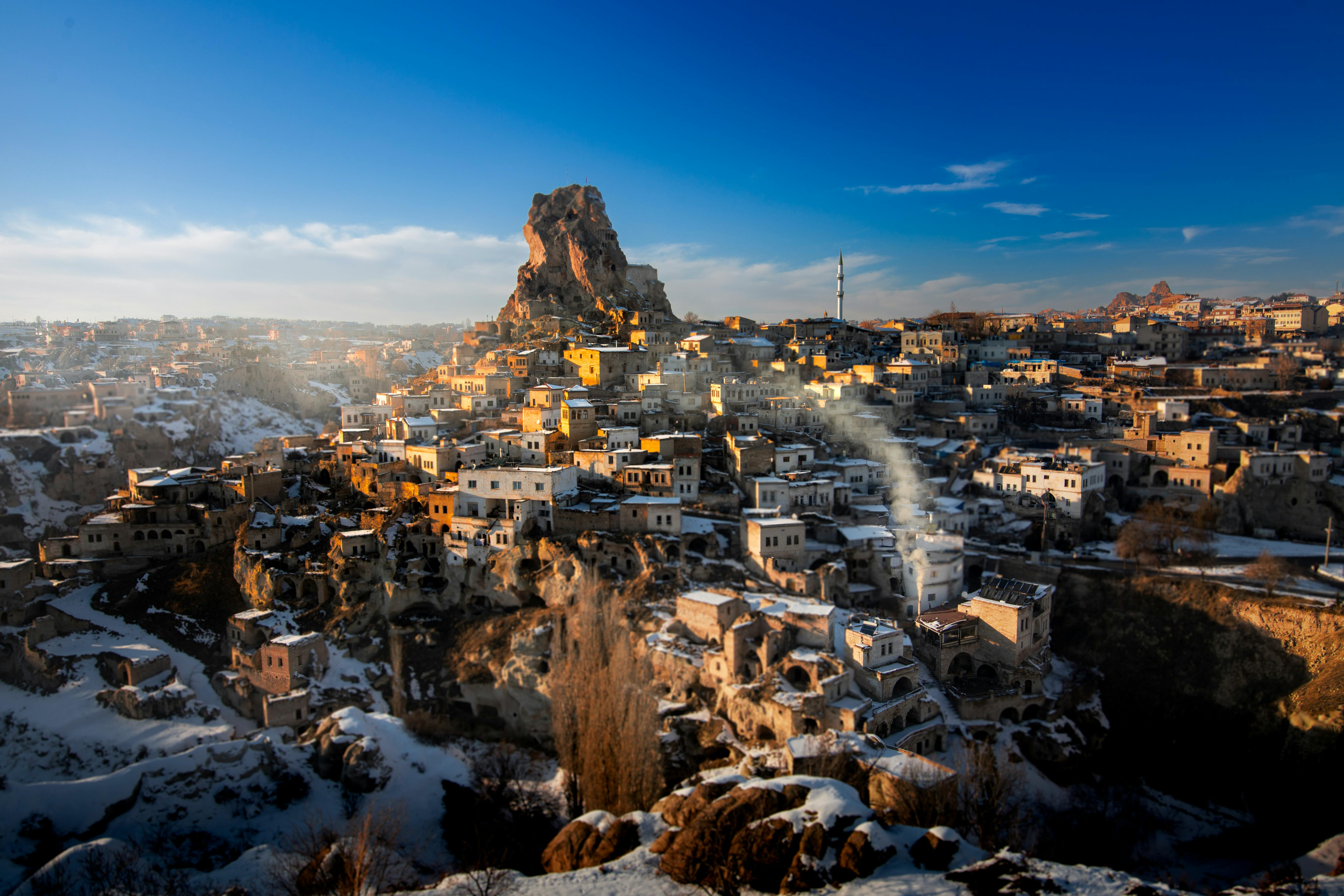 A breathtaking view of Uchisar Castle in Kayseri, Türkiye, amidst snow in a winter setting.