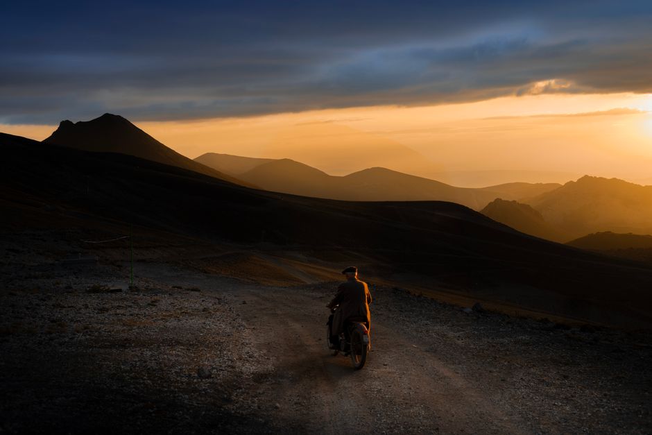 A lone motorcyclist rides along a rugged mountain path during a stunning sunset on Erciyes Mountain.
