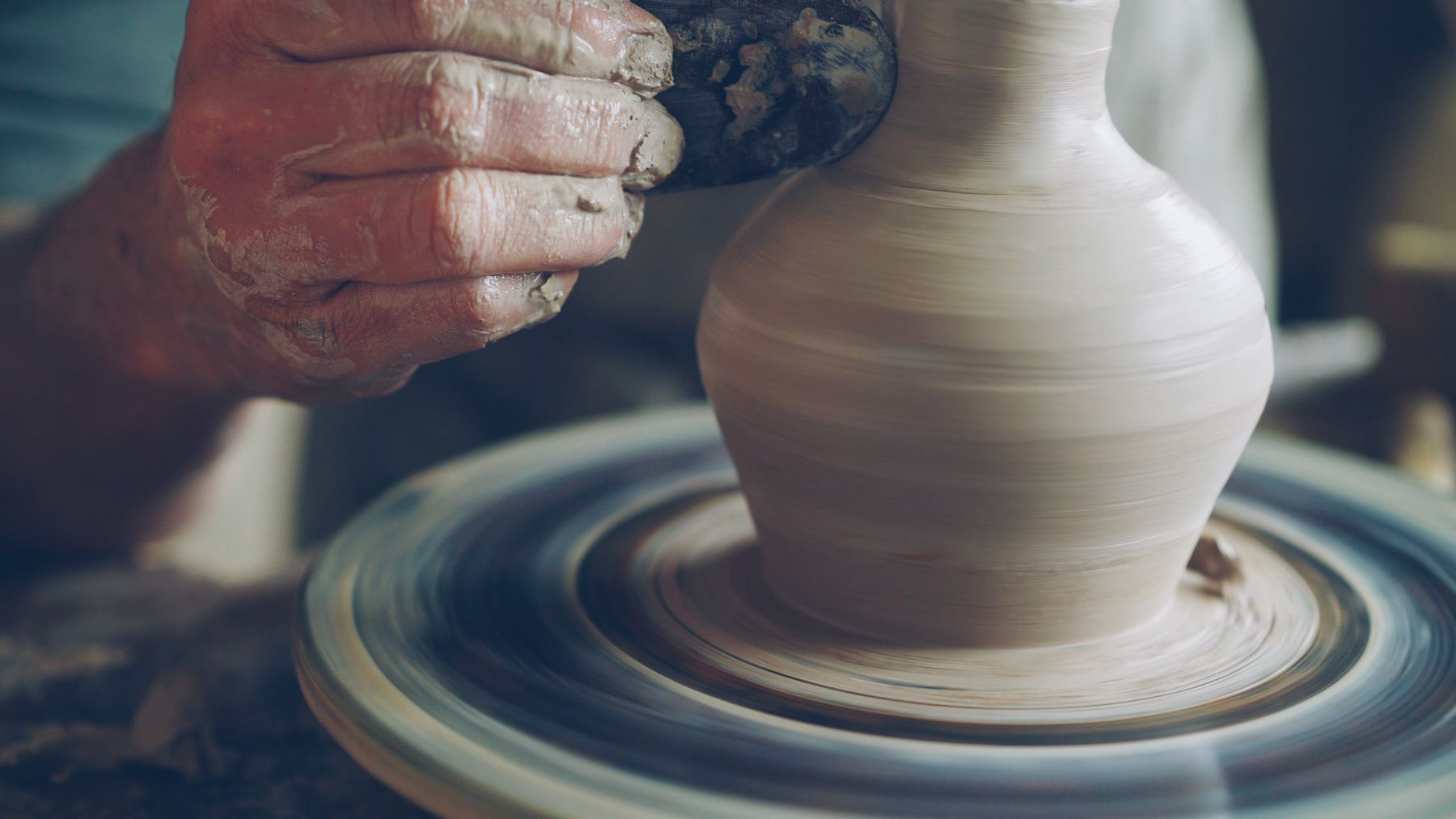 Potter shaping a ceramic vase on a pottery wheel
