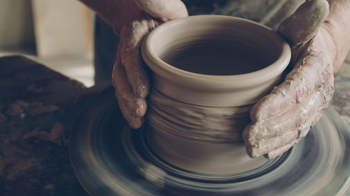 Free Hands shaping a clay pot on a spinning pottery wheel, showcasing traditional pottery techniques. Stock Photo