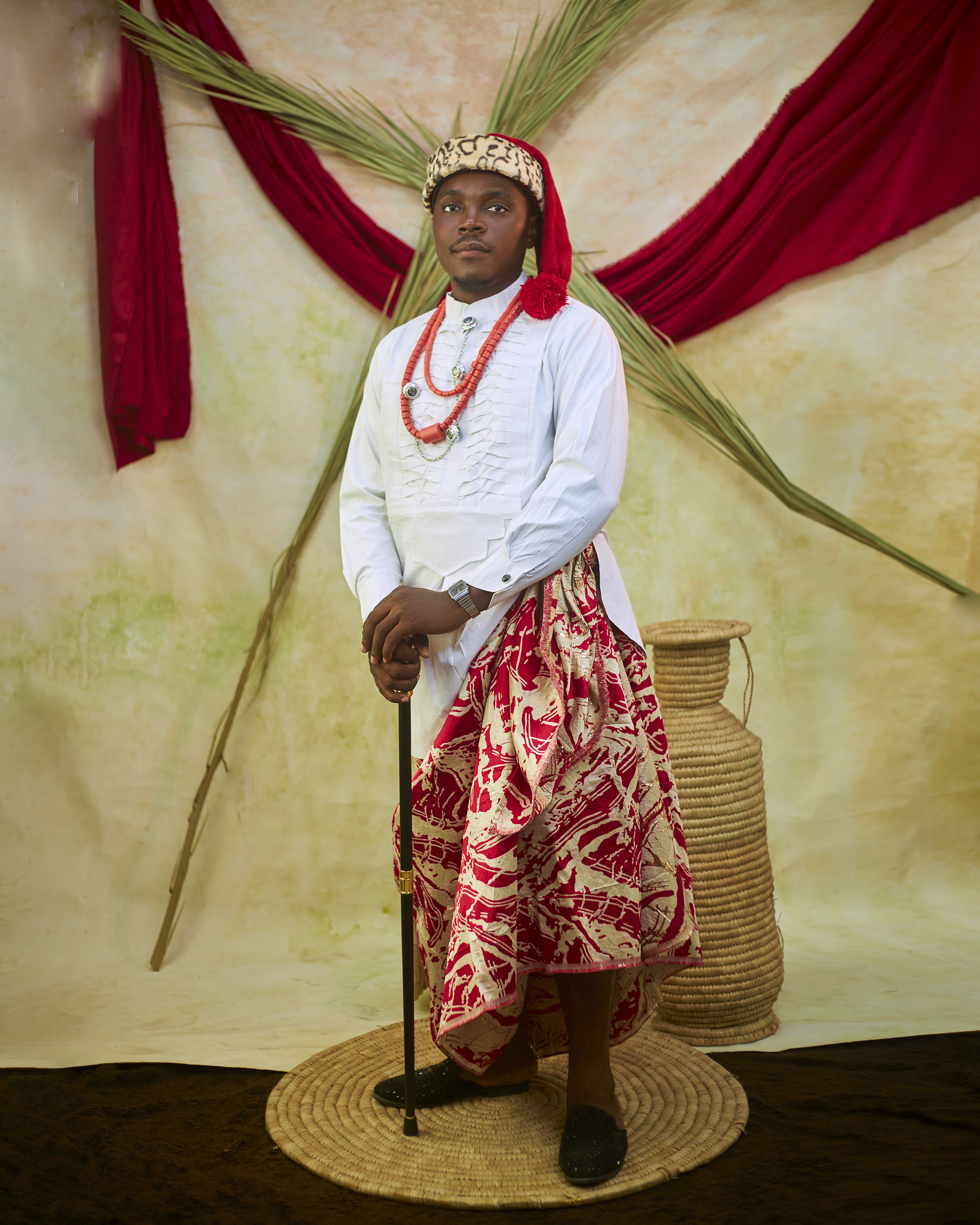 Portrait of a man in traditional African attire with cultural decor.