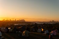 People enjoying sunset over Sydney skyline with iconic harbor views.