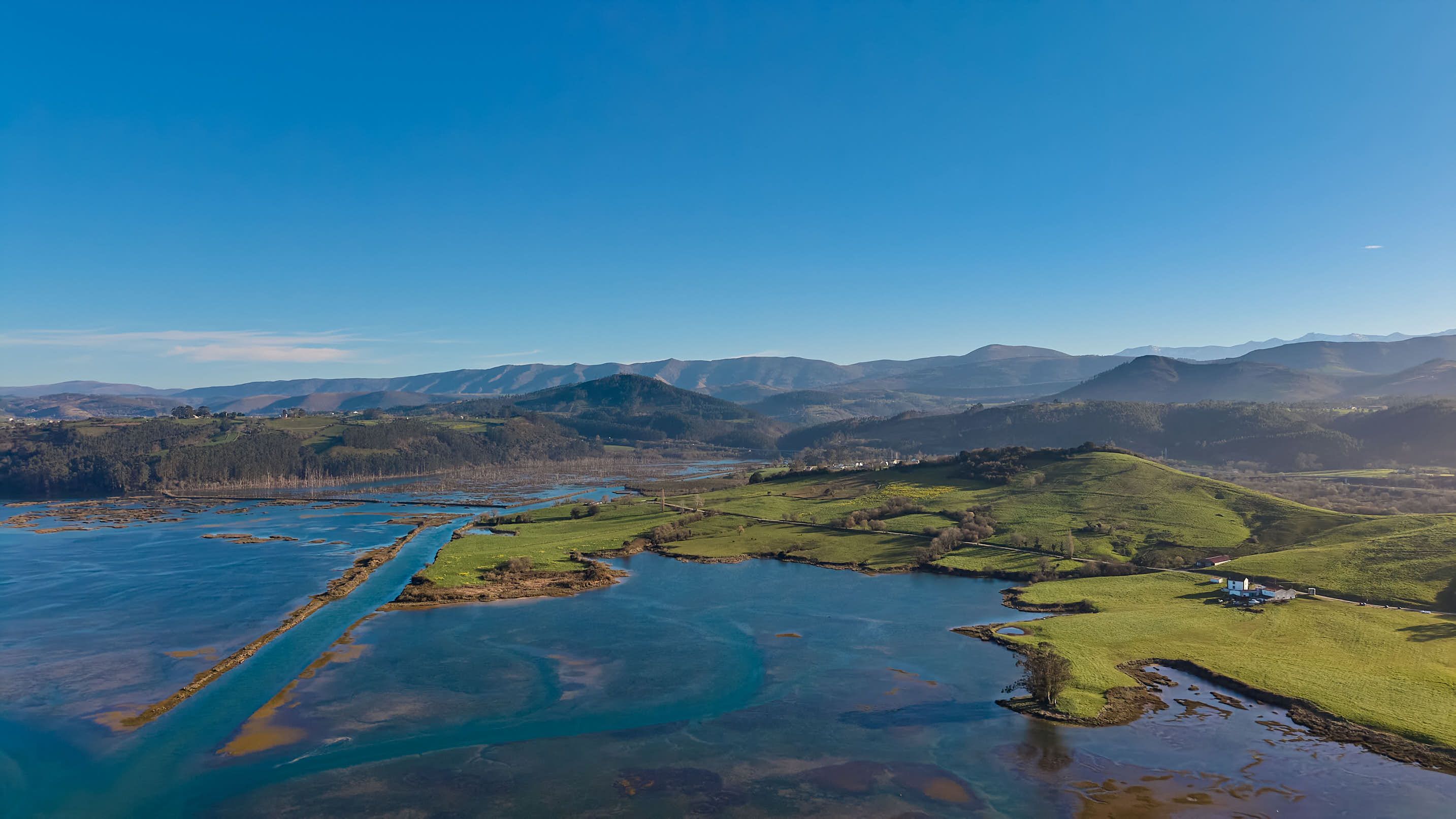 A stunning aerial view of Cantabria's coastline with lush green hills and the serene sea.