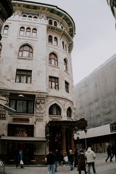 Group of people walking near a historic building in İstanbul, highlighting classic architecture.