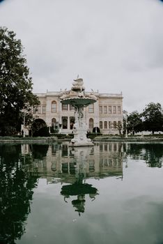 Dolmabahçe Palace and its serene reflection in a tranquil fountain, İstanbul, Turkey.